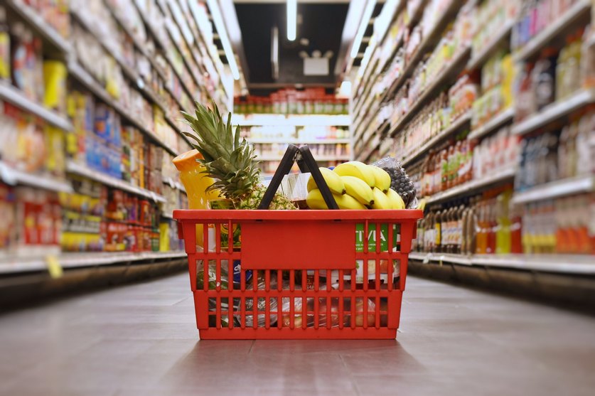 Korb mit Lebensmitteleinkauf auf dem Boden im Supermarkt: Die Lebensmittelpreise für Verbraucherinnen und Verbraucher legt der Handel fest.