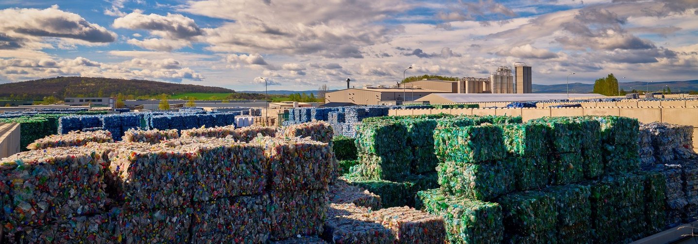 Farblich sortiertes PET-Ballenlager für das Recycling: Links ein Stapel mit transparenten und rechts ein Stapel mit grünen PET-Ballen.